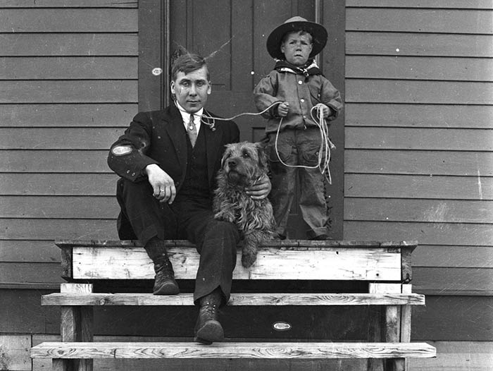 Boy in cowboy outfit with lasso around his father