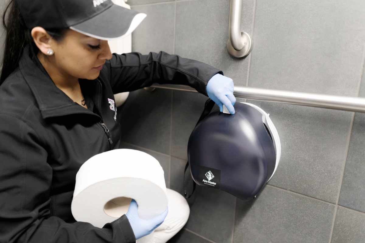 Aire-Master service rep loading toilet tissue in dispenser