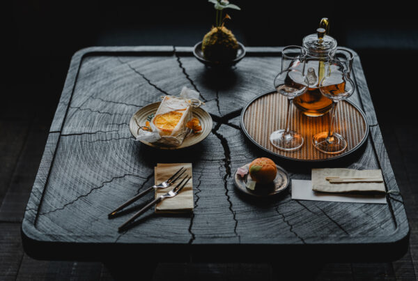 Black Chinese tea is served in glass POTS and traditional Chinese desserts are served on a black wooden table