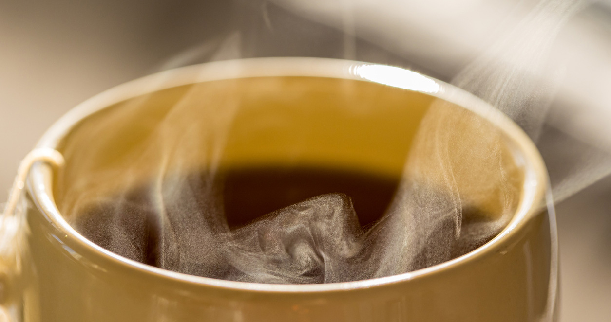 Steaming hot drink in ceramic cup close up view