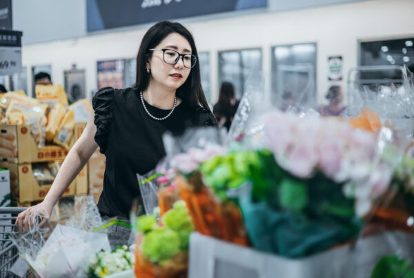 An Asian woman choosing flowers in a supermarket